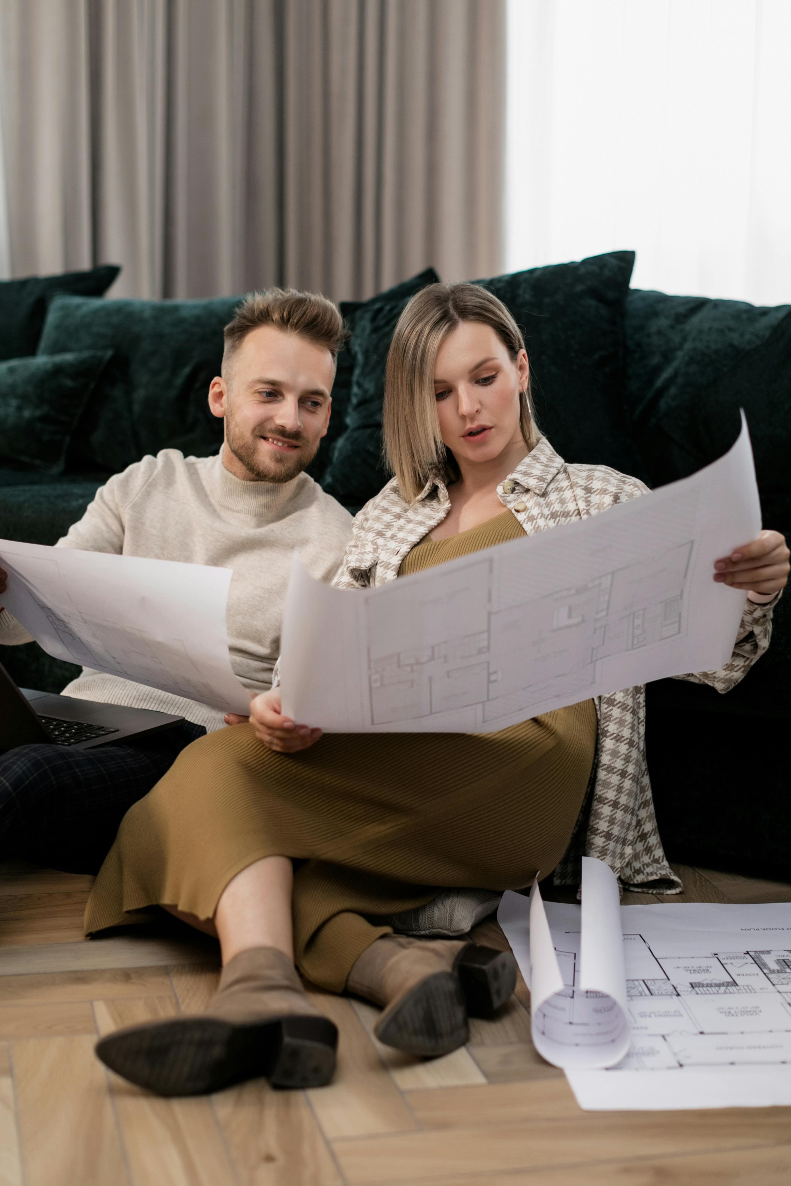 Couple smiling while comparing housing options on a laptop.